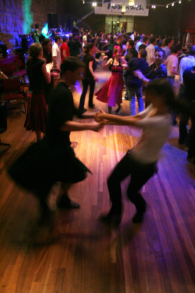 A blurry photo of a large group doing a ceilidh dance